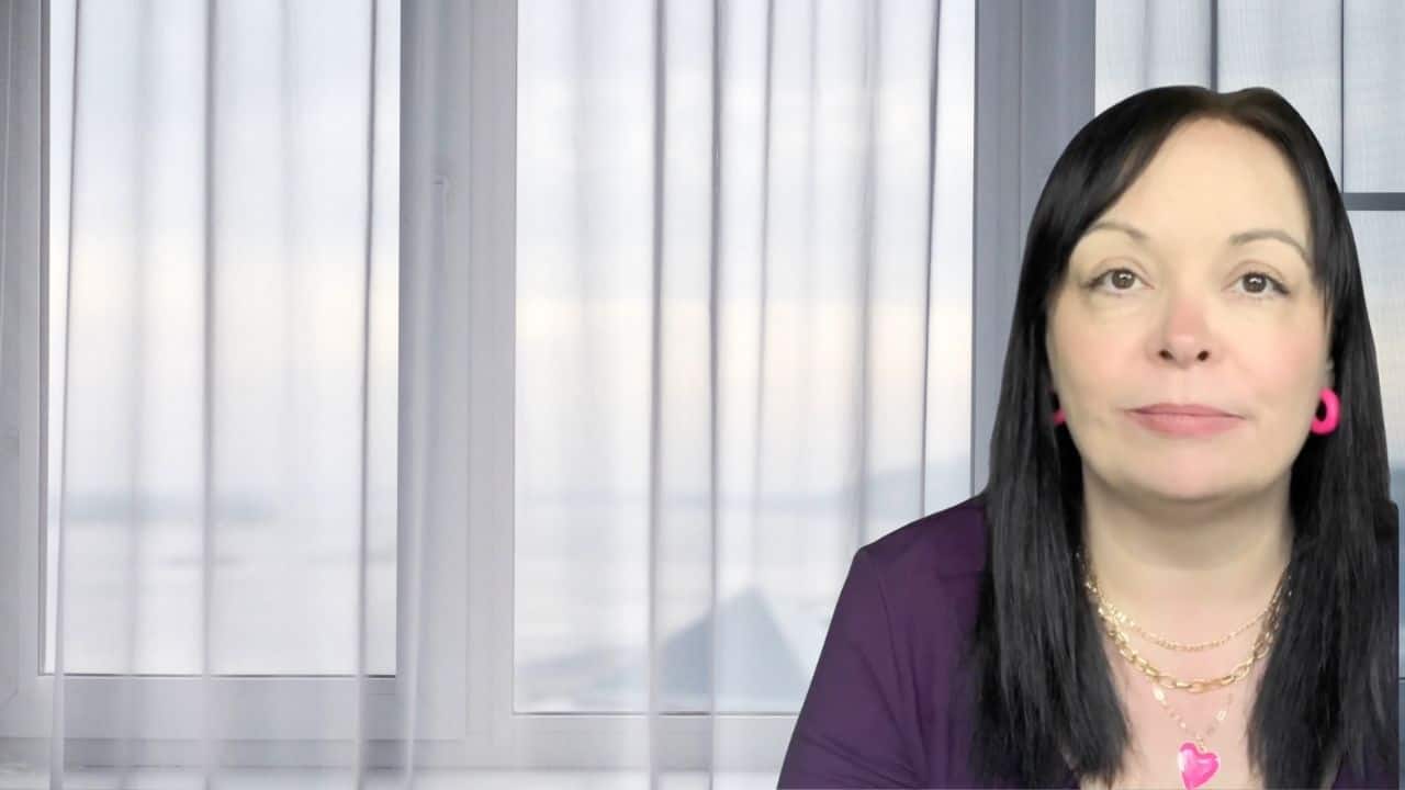 Nicky Elmer sitting in front of a softly lit window, speaking calmly about what hypnosis really is.